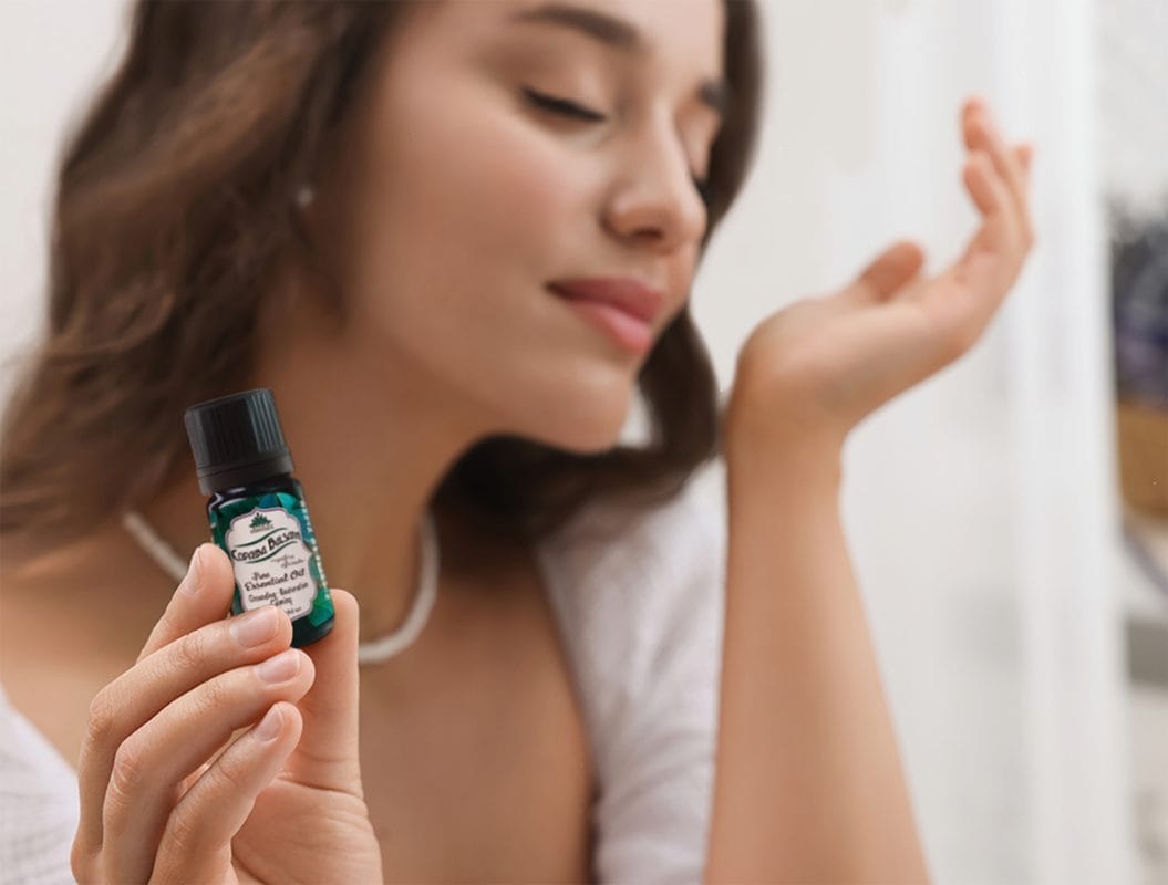 Woman smelling aroma from essential oil bottle.